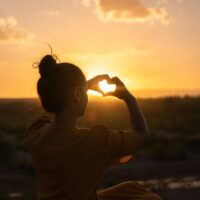 Silhouette of a person forming a heart with hands against a Morocco sunset.